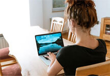 Homeoffice eine Frau die mit ihrem Laptop an einem Tisch sitzt, es soll symbolisch für Homeoffice sein